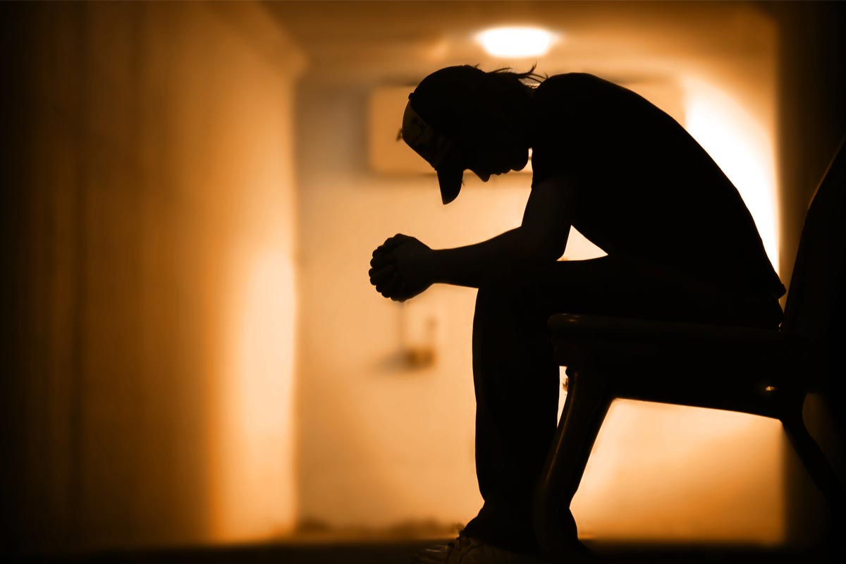 man depressed having suicidal thoughts sitting in dark hall