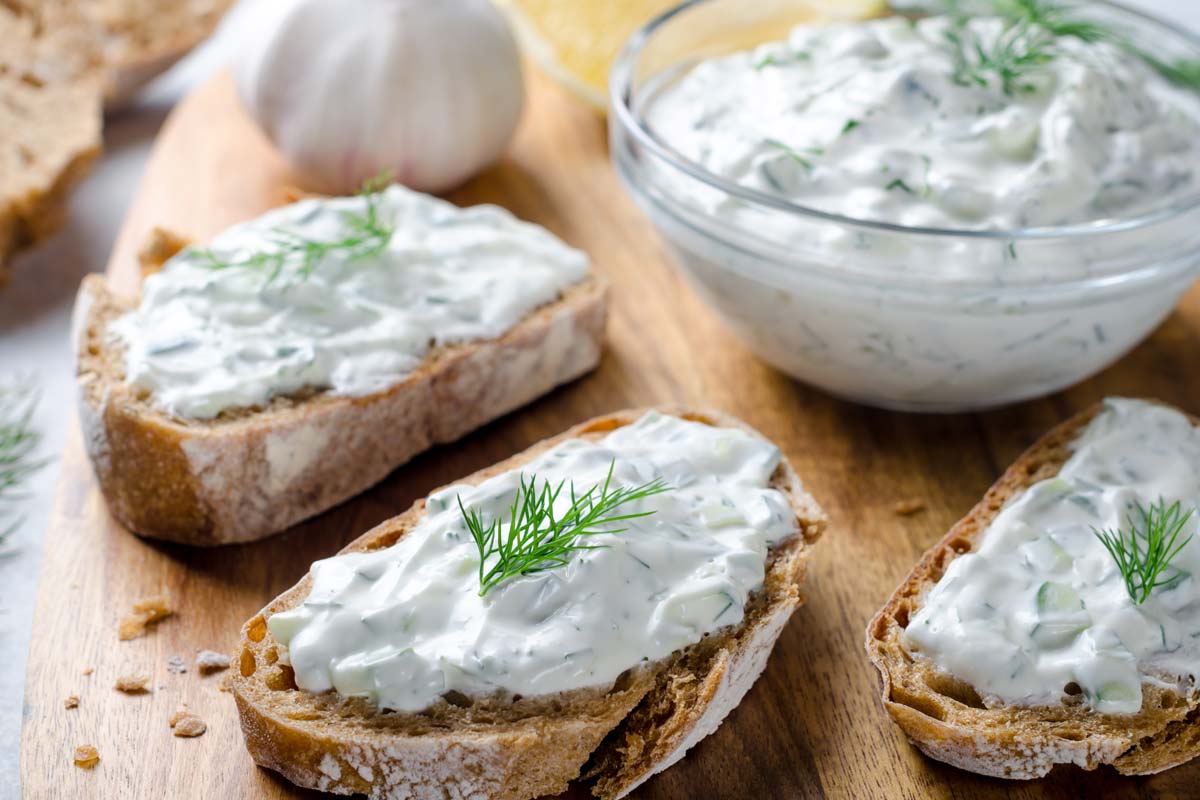Homemade greek tzatziki sauce in a glass bowl with sliced bread