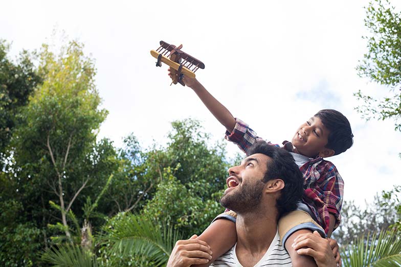 Dad carrying his son on his shoulders outdoors