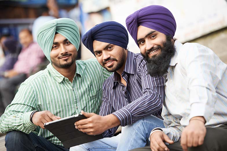 Young adult indian sikh men Punjabi men huddled around a tablet