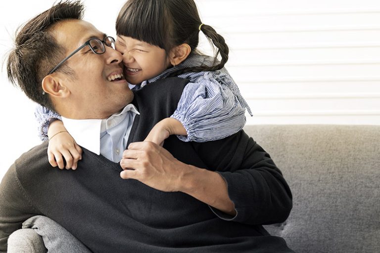 Father and daughter laughing together on the couch