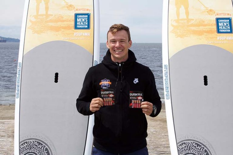 Simon Whitfield standing next to 2 stand up paddle boards