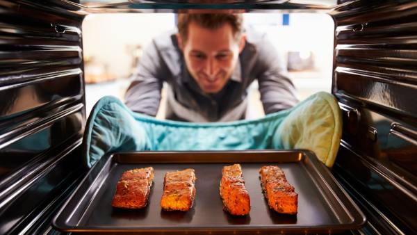 man taking salmon out of the oven