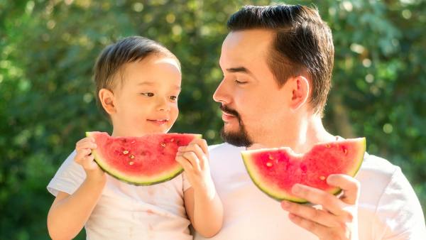 man and son eating watermelon