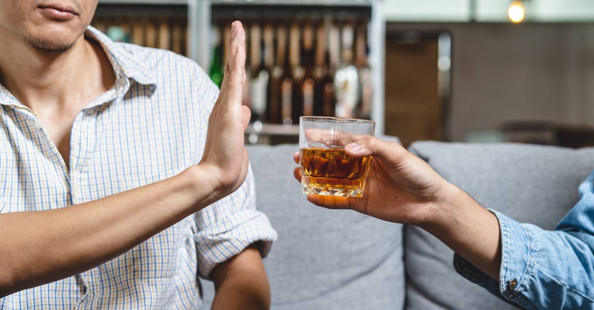 man's hand blocking drinking being handed to him