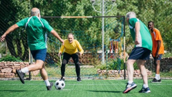 older men playing soccer outside