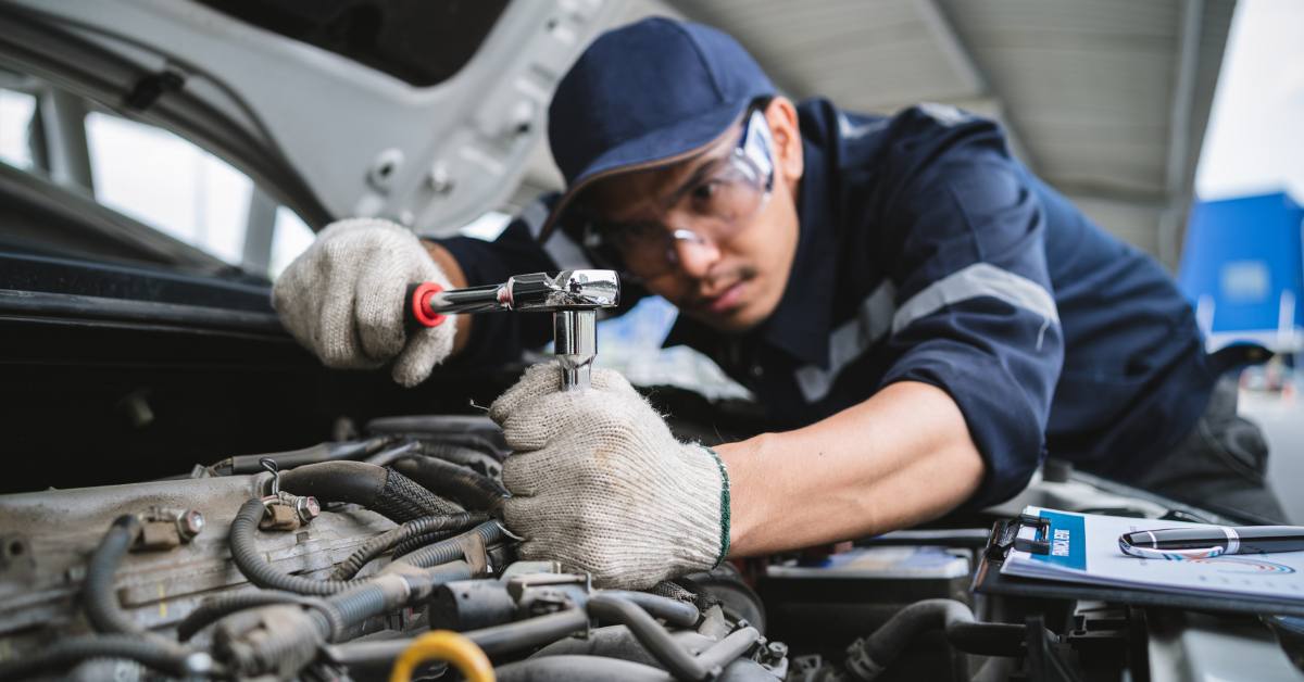 A uniformed maintenance technician is working on a vehicle inspection service.