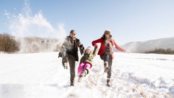 Father and mother with their daughter, playing in the snow.