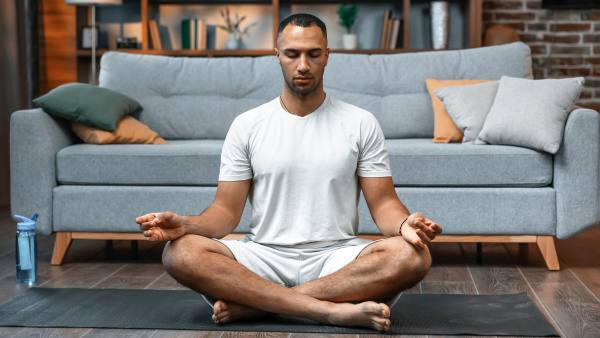 Young man meditating on his living room floor