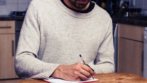 black man at kitchen table writing notes
