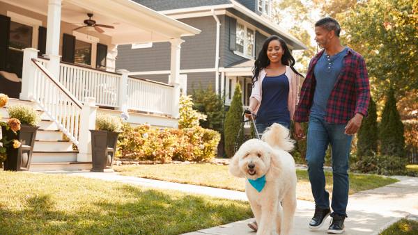 man and woman outside on residential street walking their dog