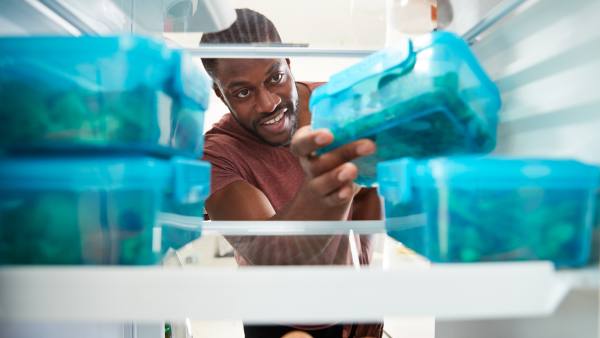 man reaching into fridge with blue meal-prep containers