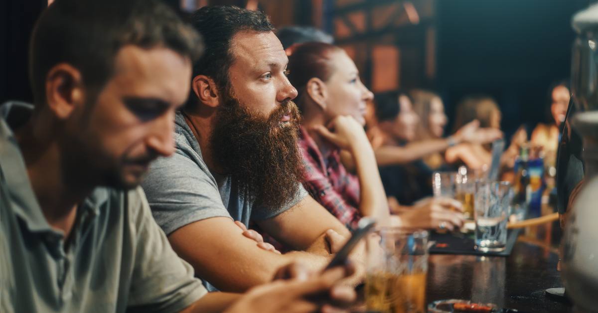 sad man sitting at bar starring blankly with empty beer glass
