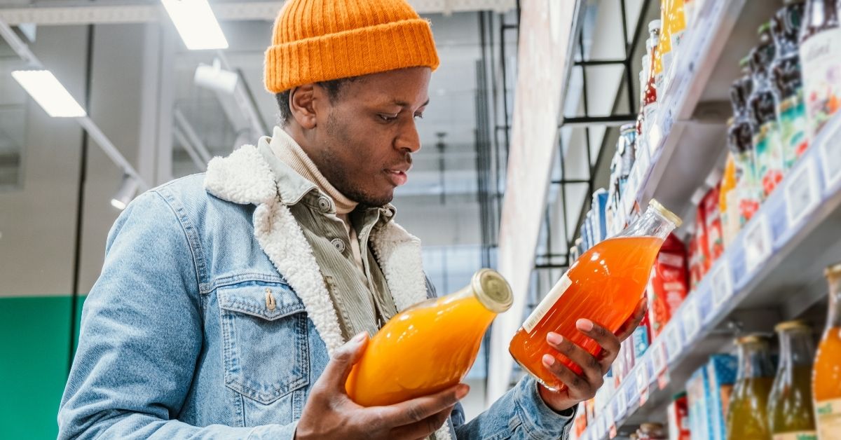 man choosing juice at grocery store