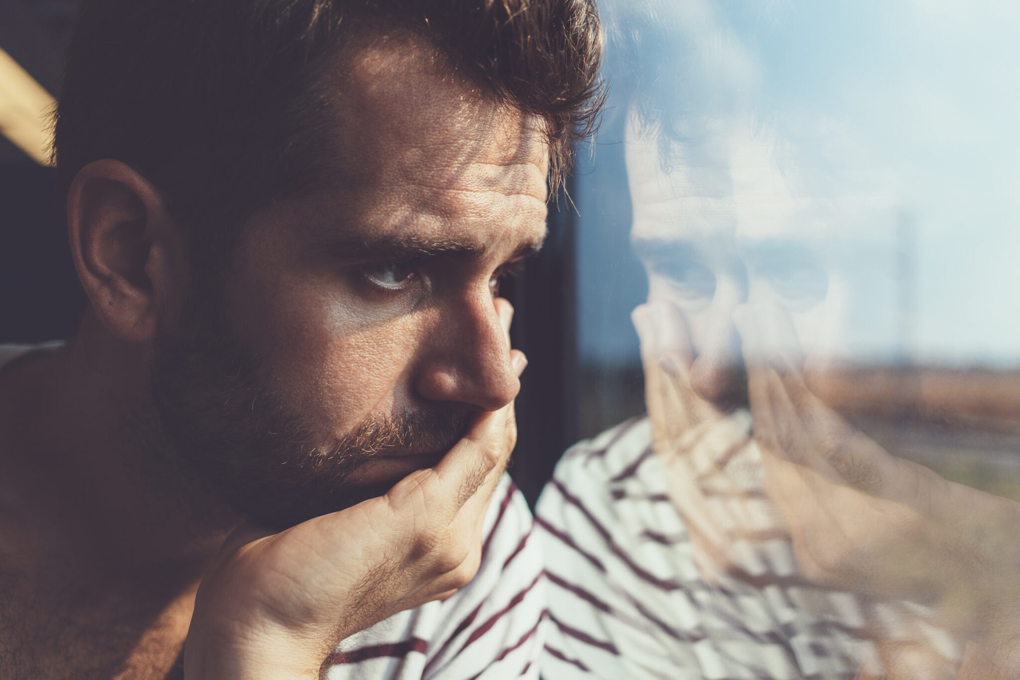 man looking sad out the window
