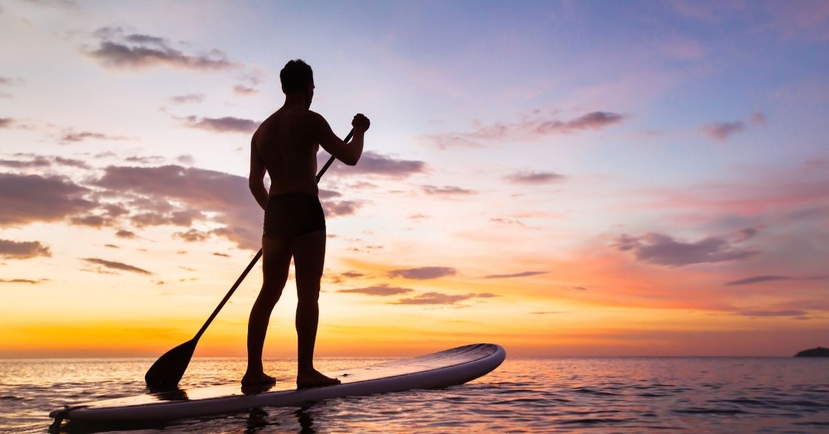 man paddleboarding with sunset