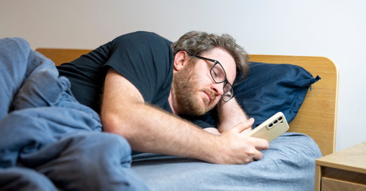 man lying in bed reading his phone